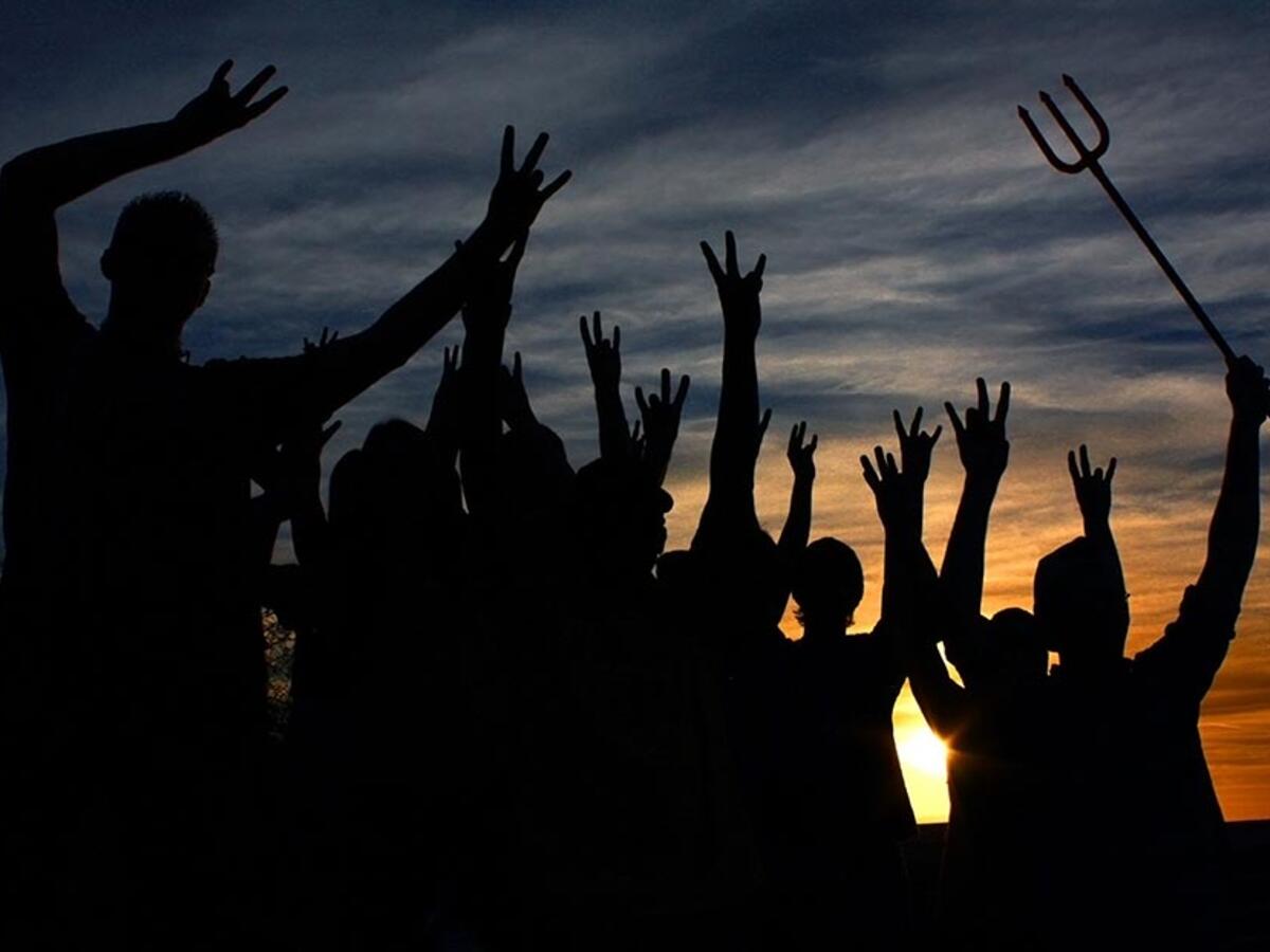 people looking at sunset with pitchfork hand signs 